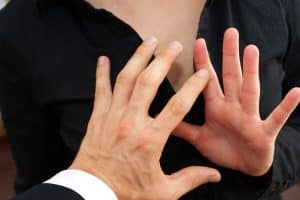 Business man sexually harassing female colleague by trying to touch her breasts