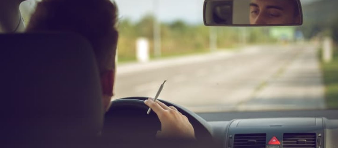 man driving with joint in hand
