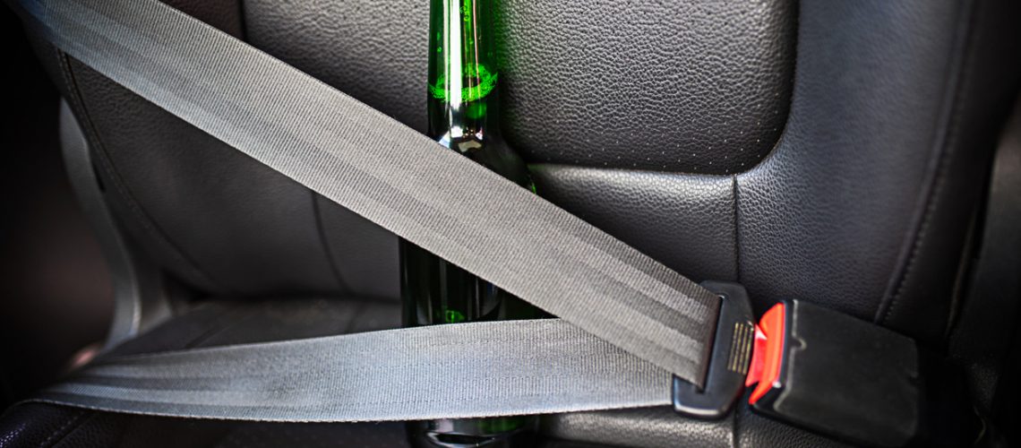 Bottle of alcohol fastened with seat belts. Drink and drive. Bottle of beer inside the car. Don't Drink for Drive.
